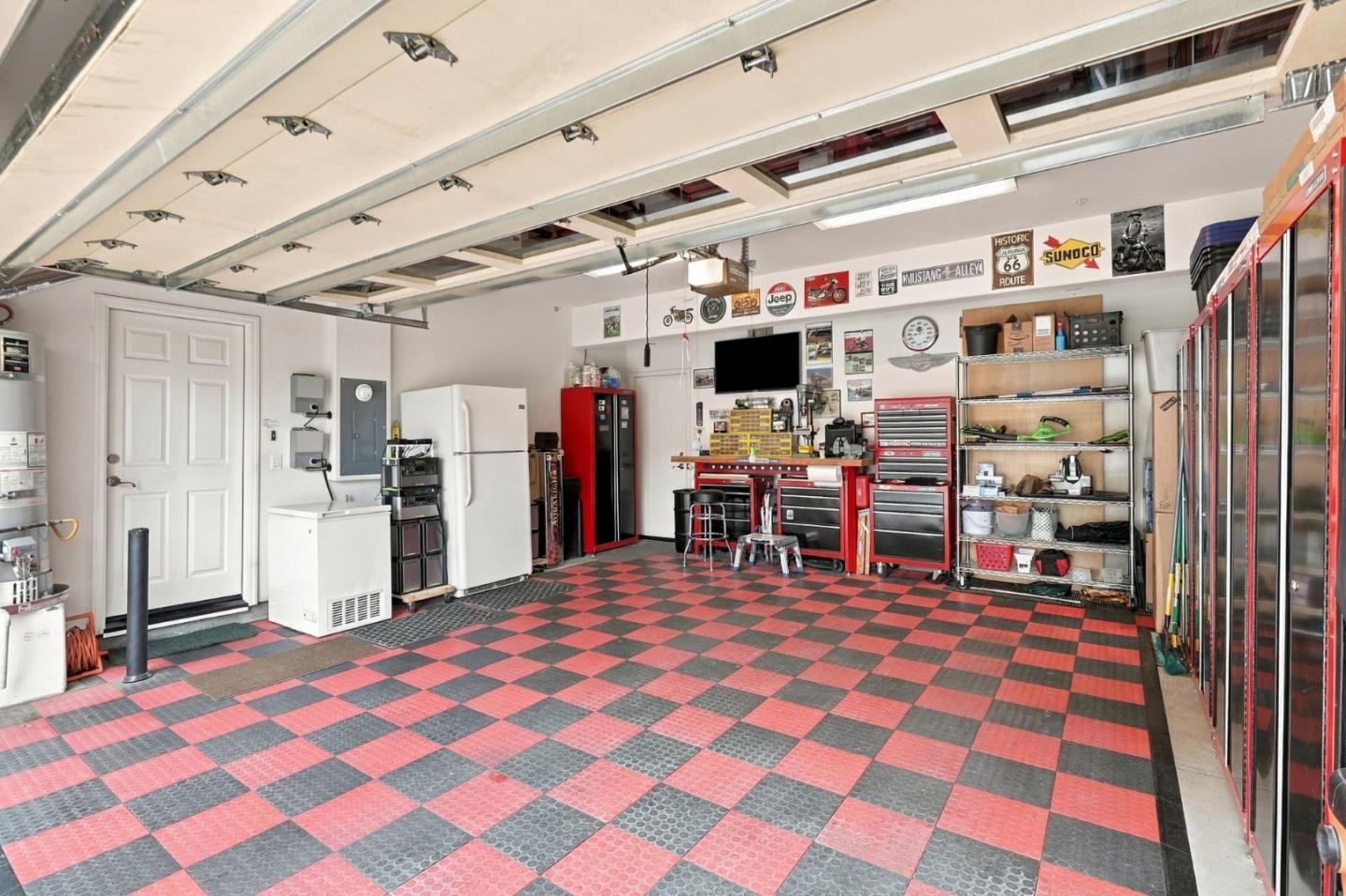 Garage workshop with a red-and-black checkerboard floor, red tool cabinets, and automotive signs.