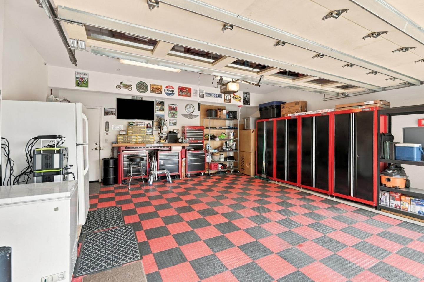 Garage with a red-and-black checkerboard floor, tool cabinets, and workbenches.