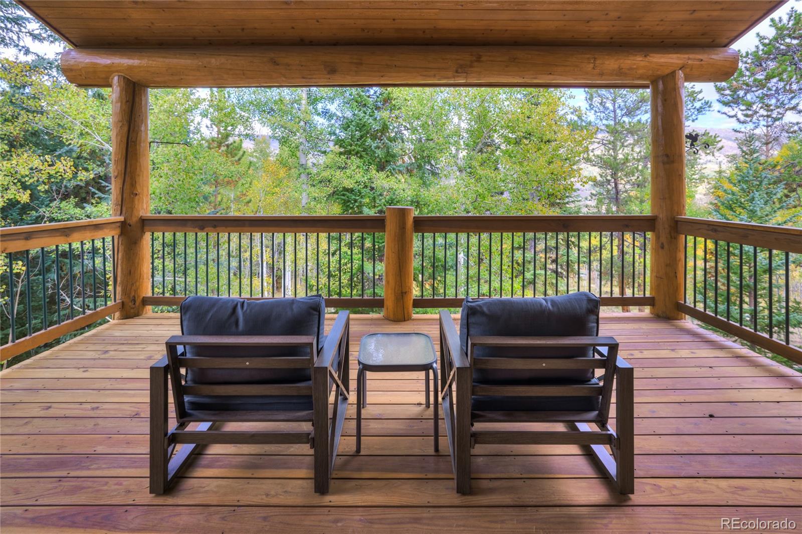 Covered timber deck with two lounge chairs overlooking autumn trees.
