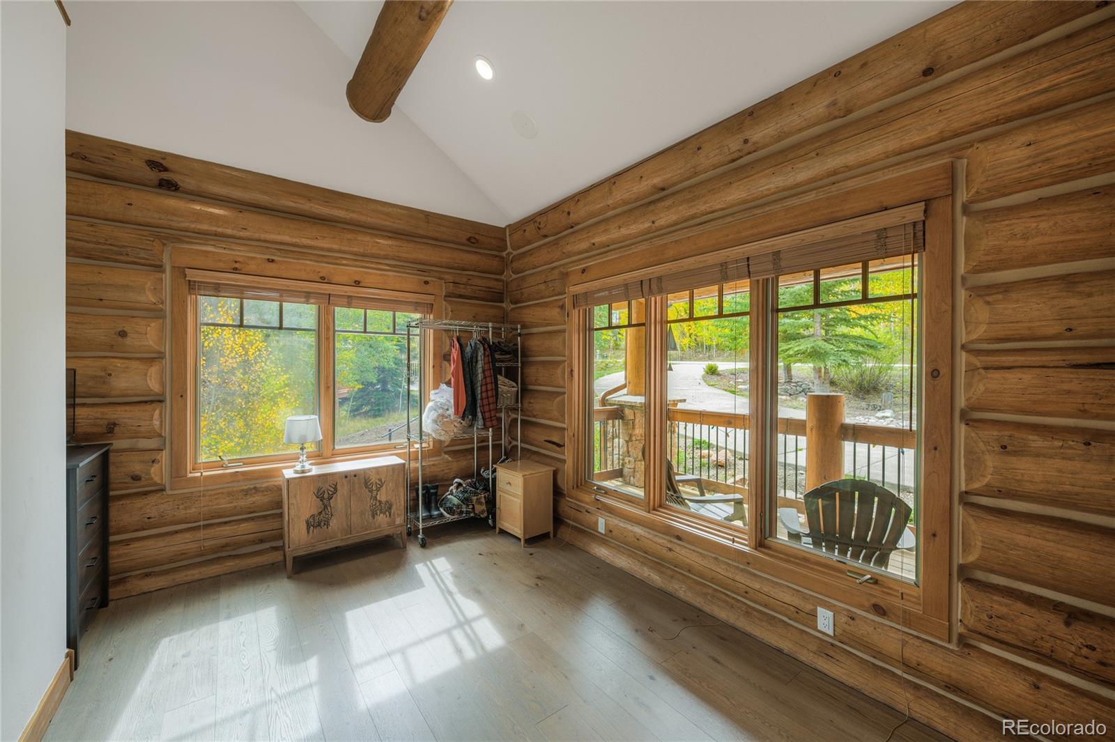 Log-cabin room with exposed beams, large windows, and a glass door to the porch.