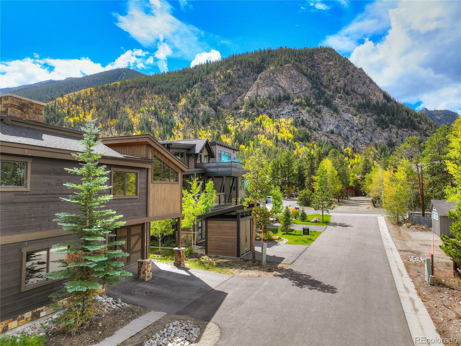 Modern townhomes on a Frisco street, backed by autumn trees and rugged mountain peaks.