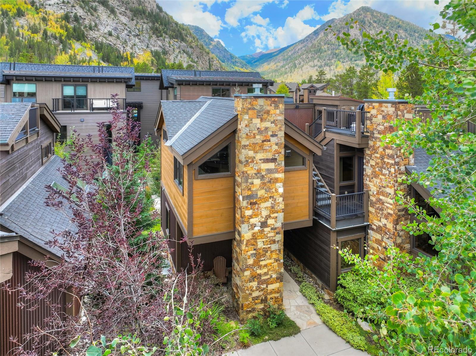 Modern townhomes with stone chimneys and mountain views amid autumn foliage.