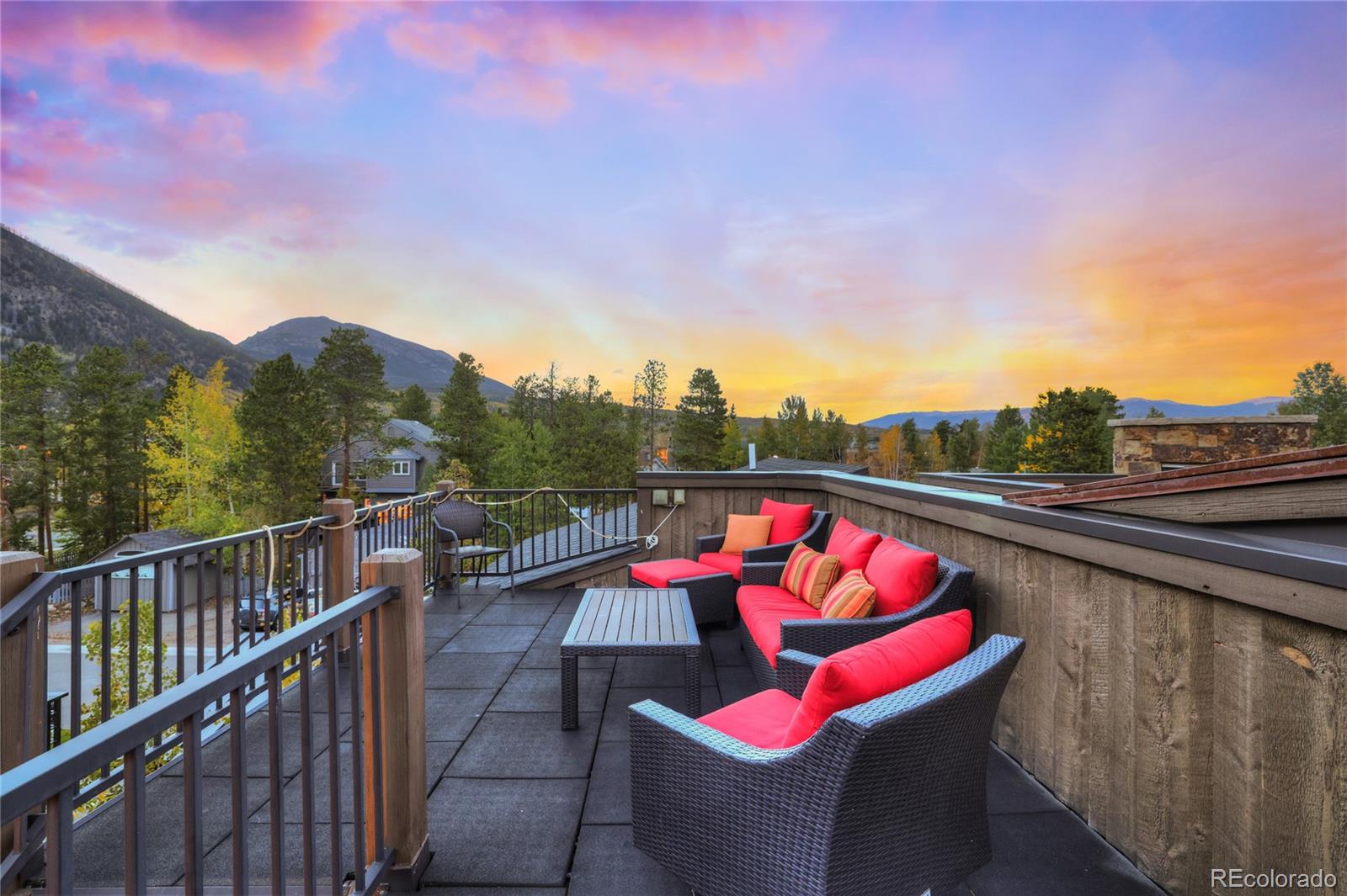 Rooftop deck with red outdoor seating and mountain views at sunset.