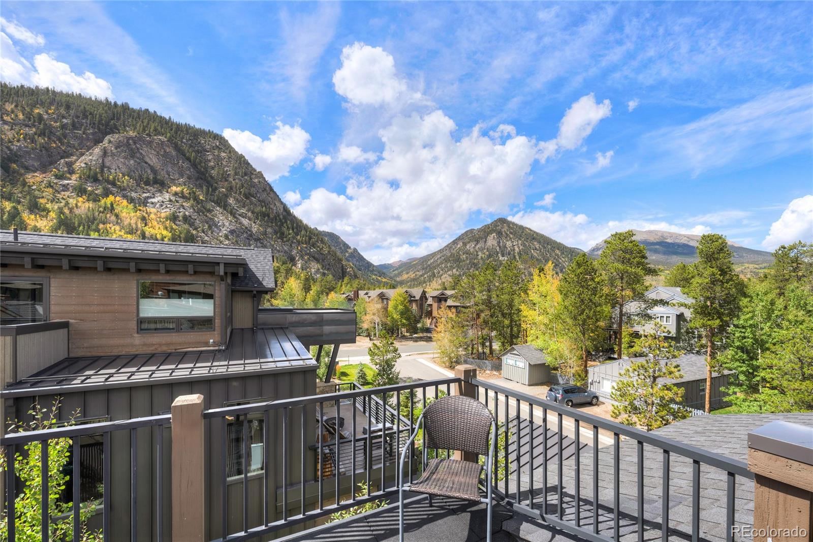 Rooftop deck overlooking Frisco’s mountain valley, with a woven chair, autumn trees, and a wide blue sky.