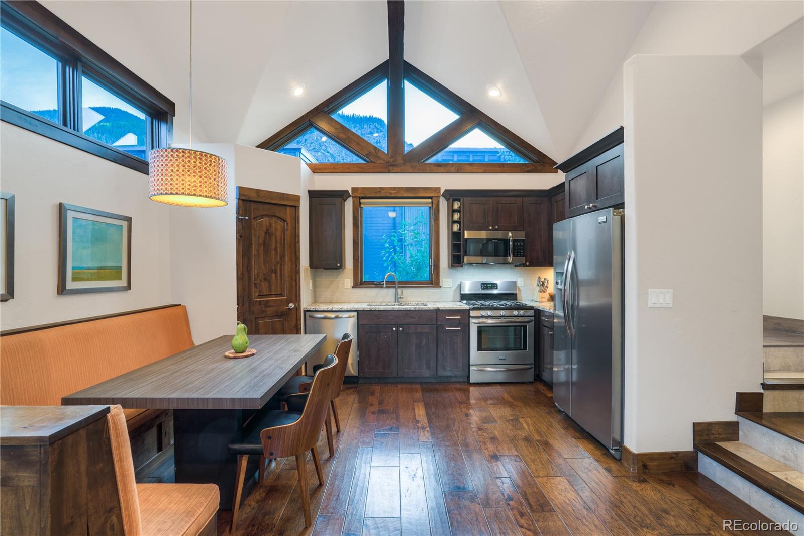 Kitchen and dining area with vaulted triangular windows, dark wood cabinetry, and mountain views.