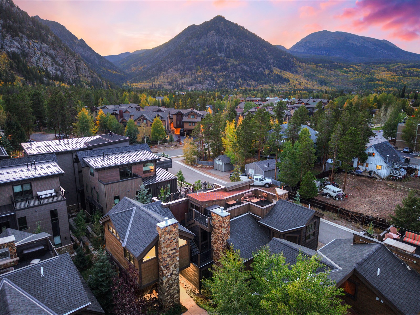 Aerial view of Frisco homes and rooftops against autumn mountains at dusk.