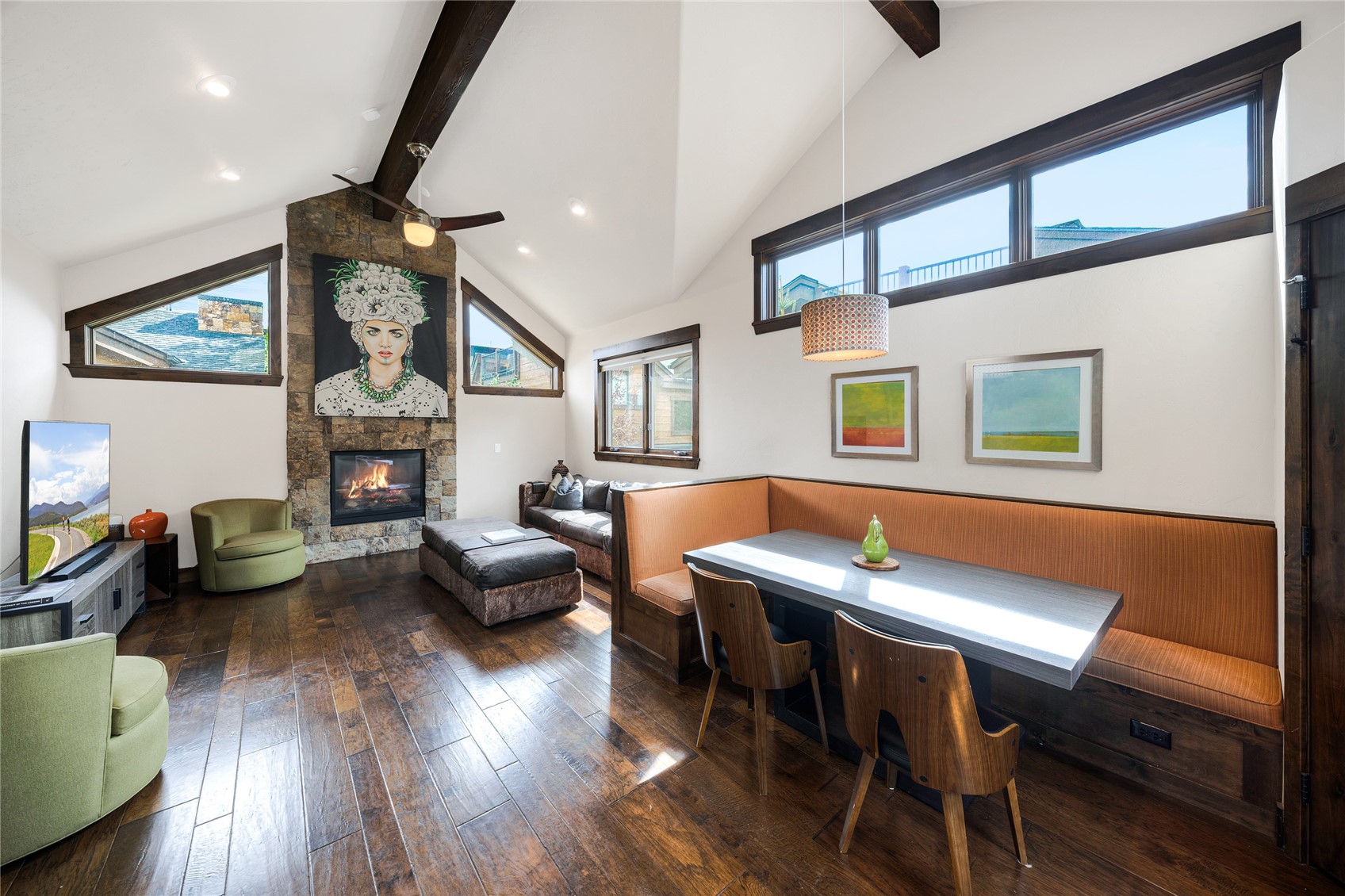 Living and dining area with a vaulted ceiling, stone fireplace, and orange built-in booth.