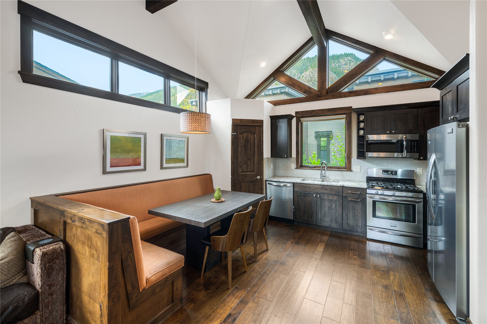 Kitchen and dining nook with a built-in banquette, vaulted windows, and mountain views.