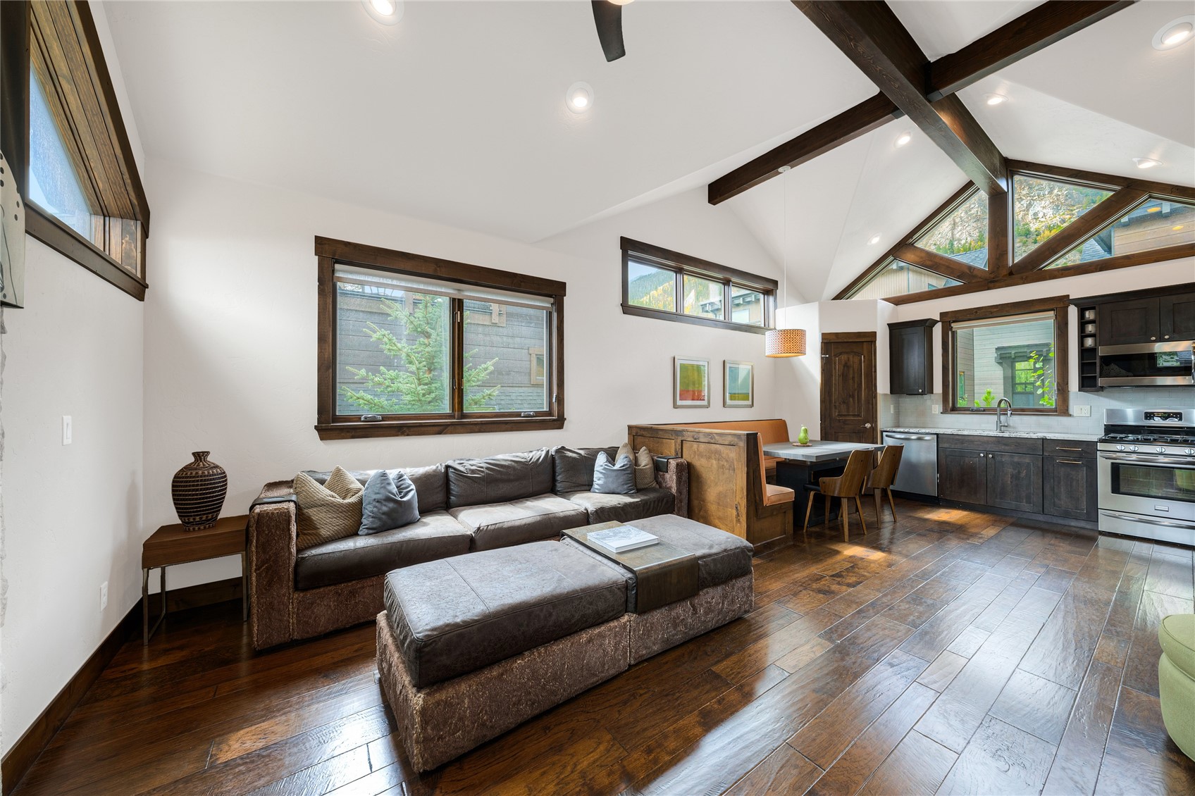 Living room with a sectional sofa, exposed wood beams, and mountain views through large windows.