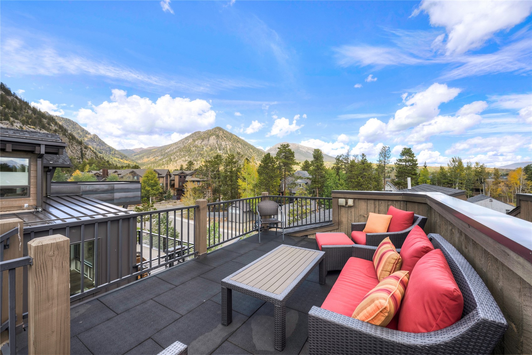 Rooftop deck with red-cushioned wicker seating and mountain views.