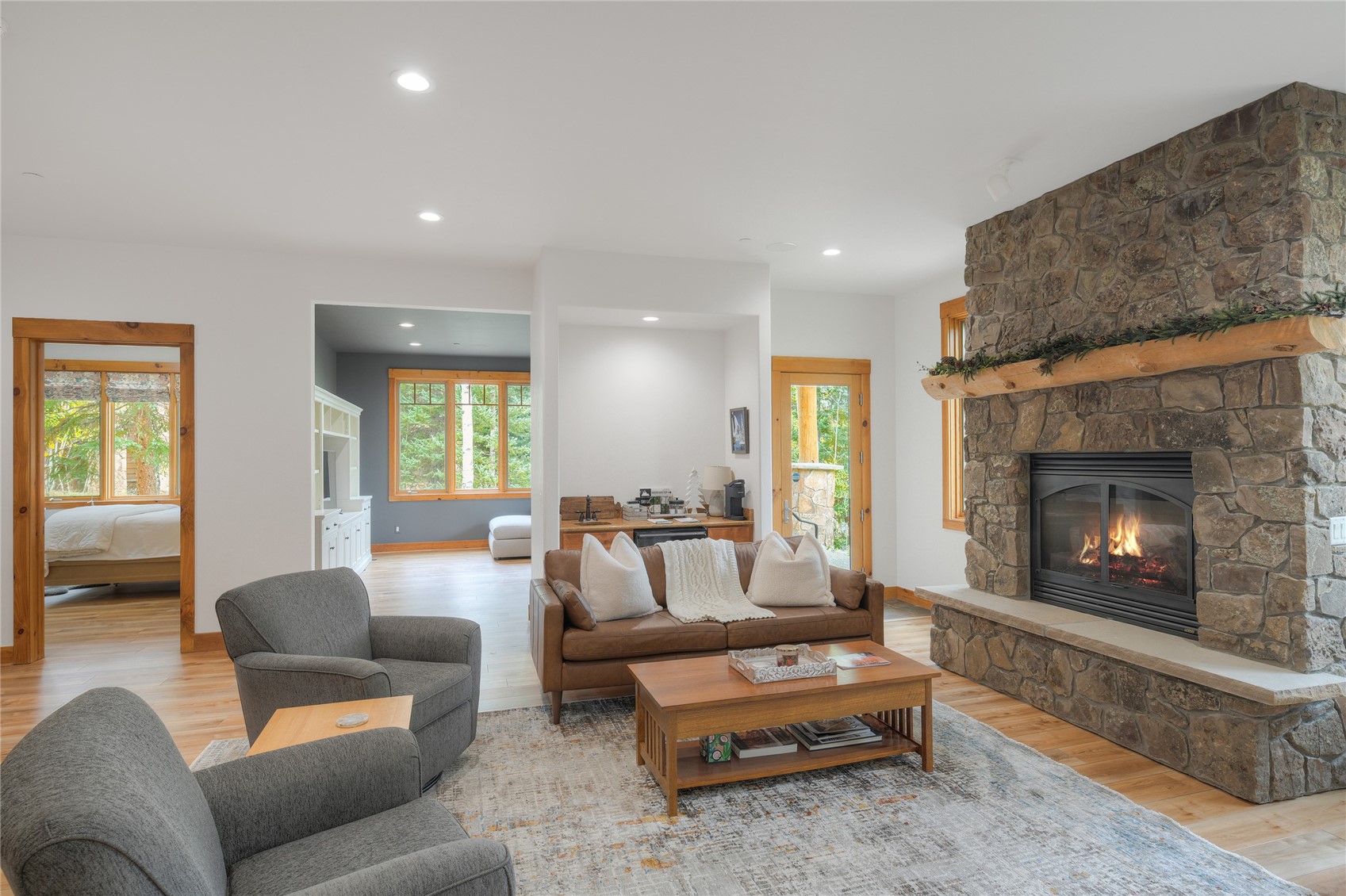 Living room with a stone fireplace, wood mantel, and seating around a coffee table.