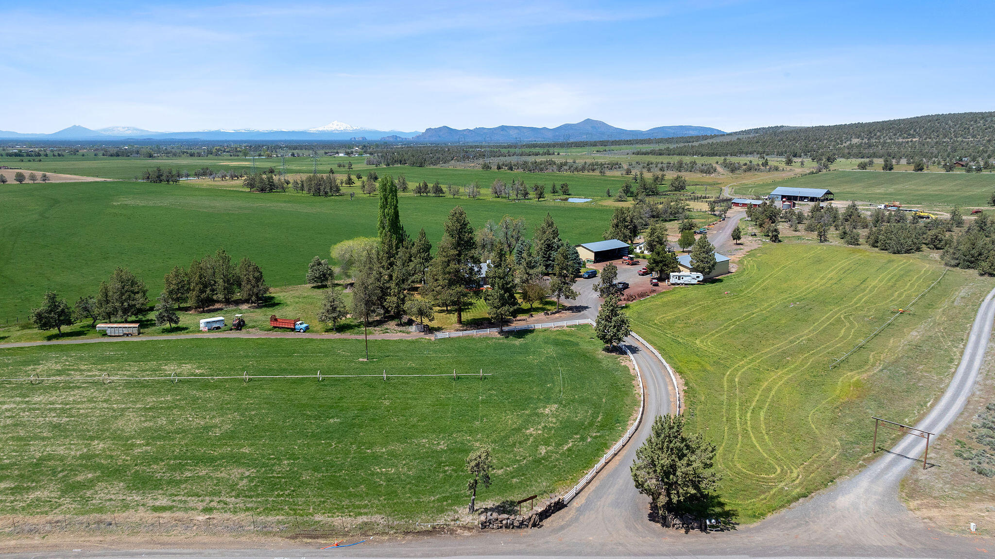 Aerial view of ranch pastures and farm buildings, with mountains along the horizon.
