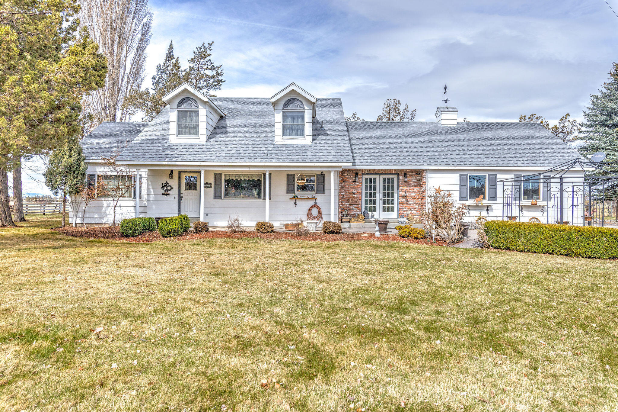 White ranch home with twin dormers, a brick entry section, and a broad front lawn.