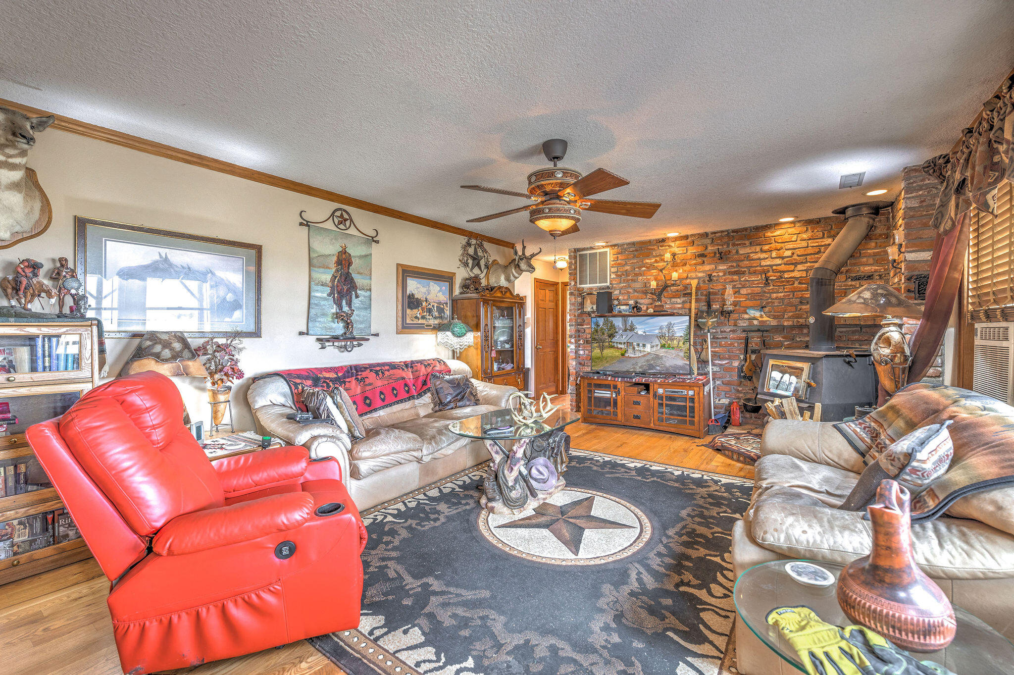 Living room with a brick wall, wood stove, and bright red recliner.
