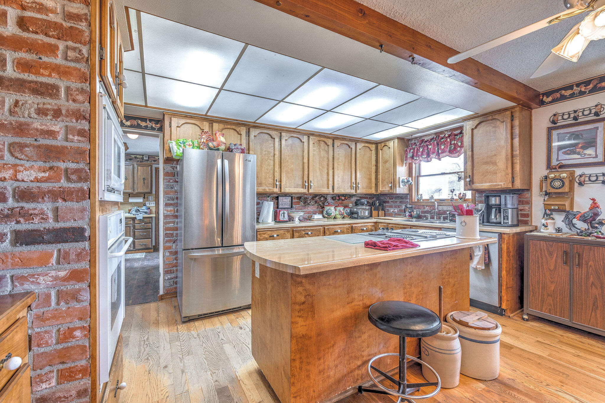Kitchen with a large wood-topped island, brick walls, extensive cabinetry, and stainless steel appliances.