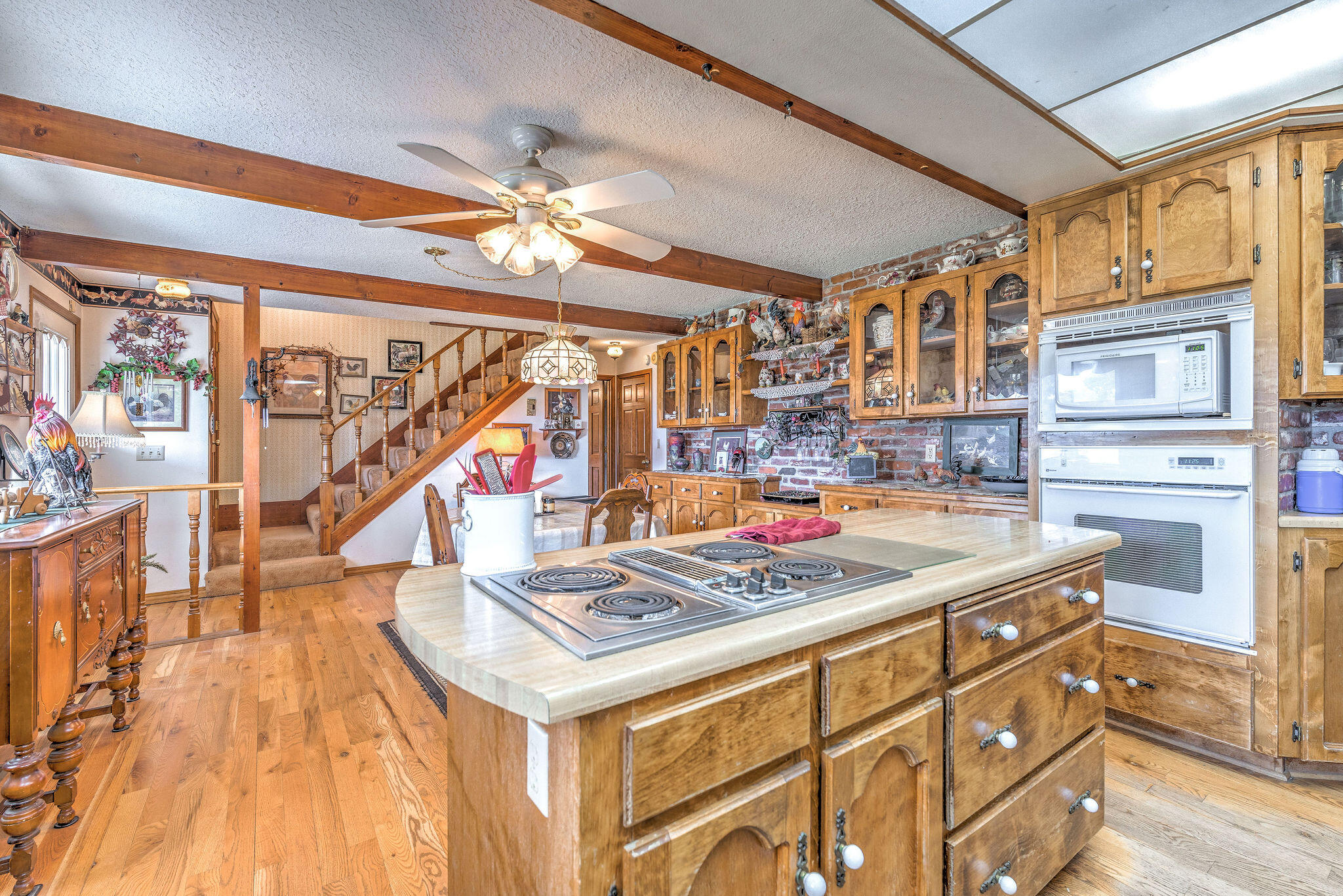 Rustic kitchen with a large cooktop island, exposed beams, and wood cabinetry.