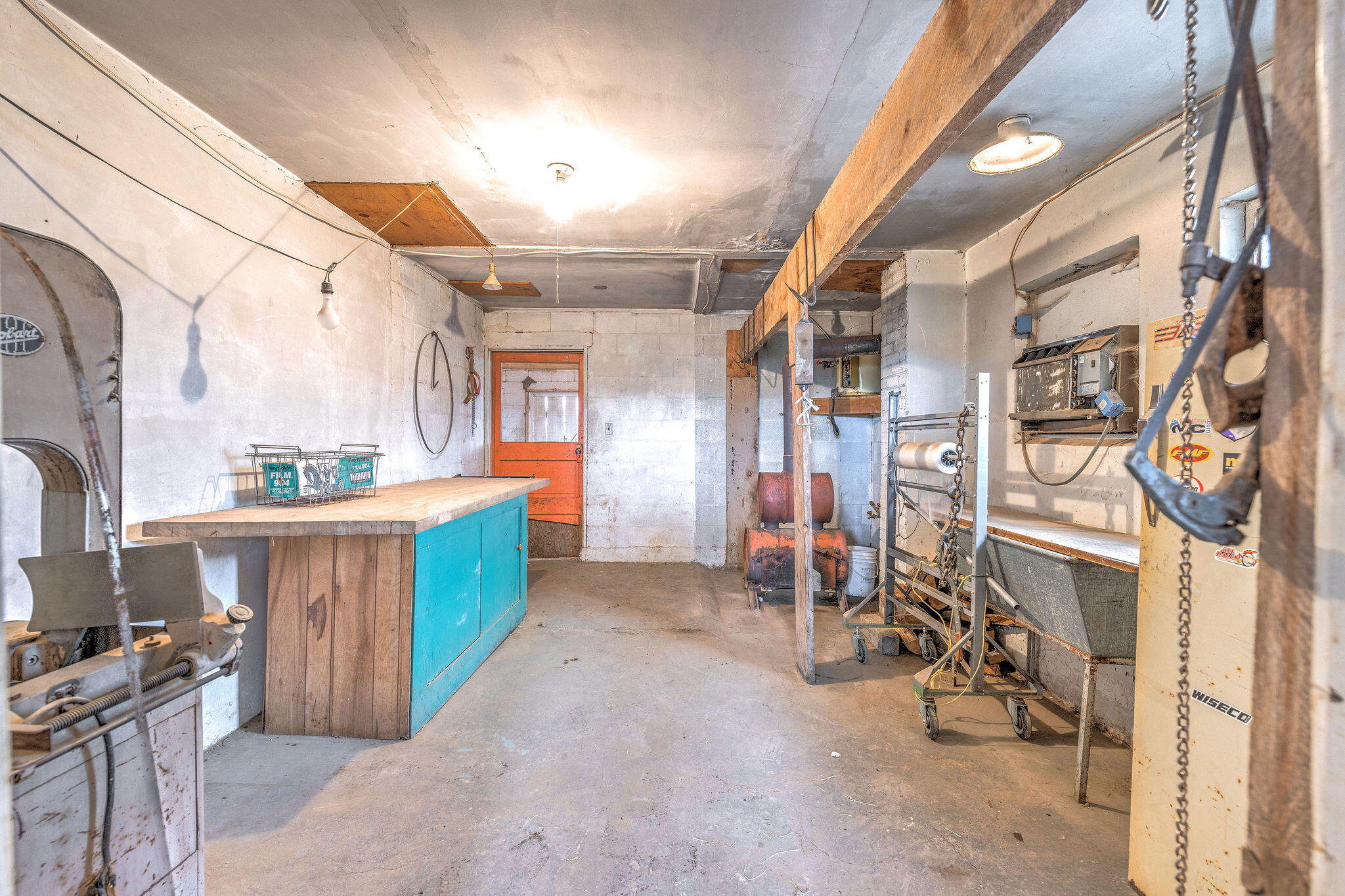 Workshop with a turquoise workbench cabinet, concrete block walls, and machinery and equipment.