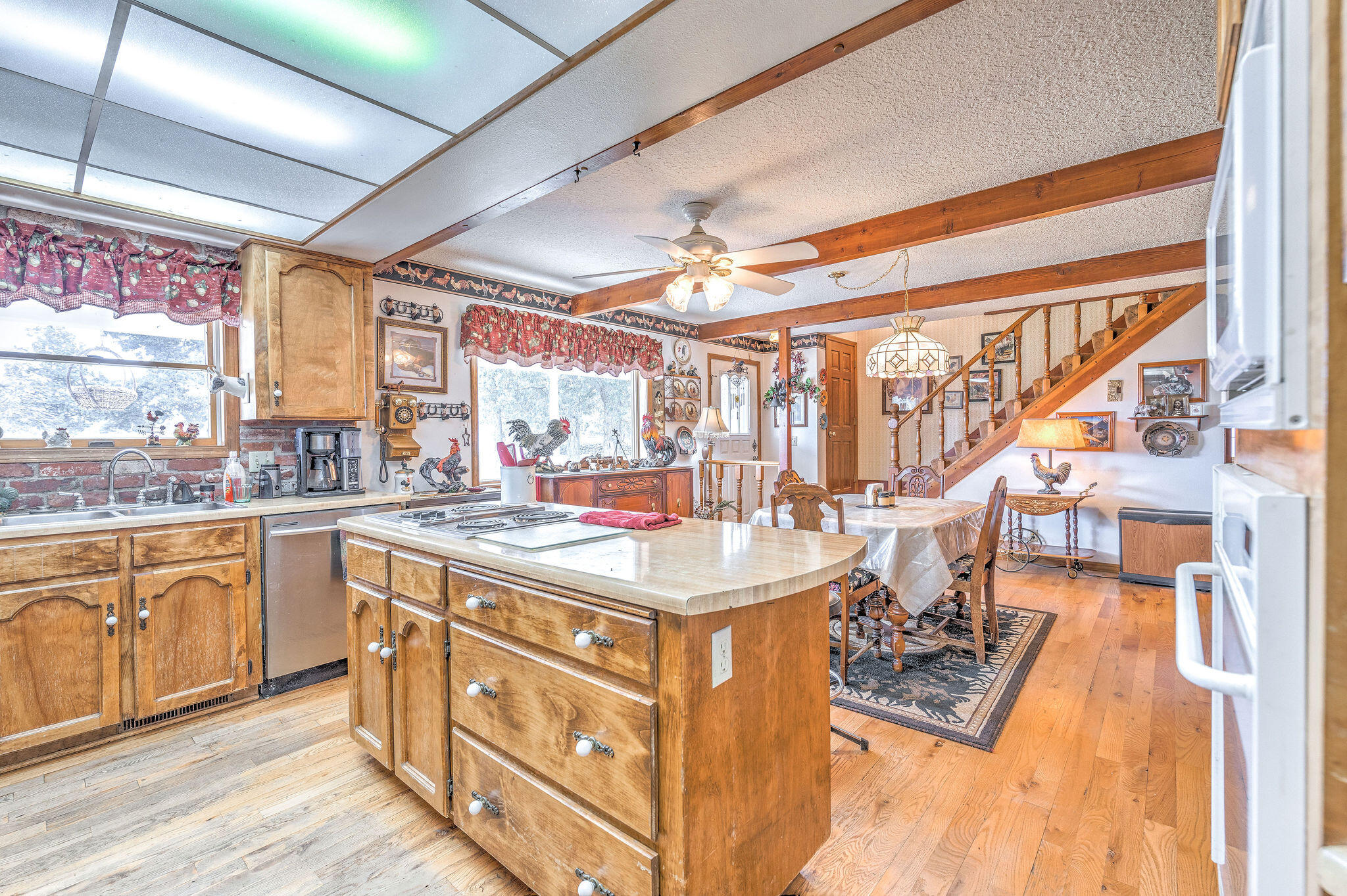 Rustic kitchen with a large wood island, exposed beams, and an adjoining dining area and staircase.
