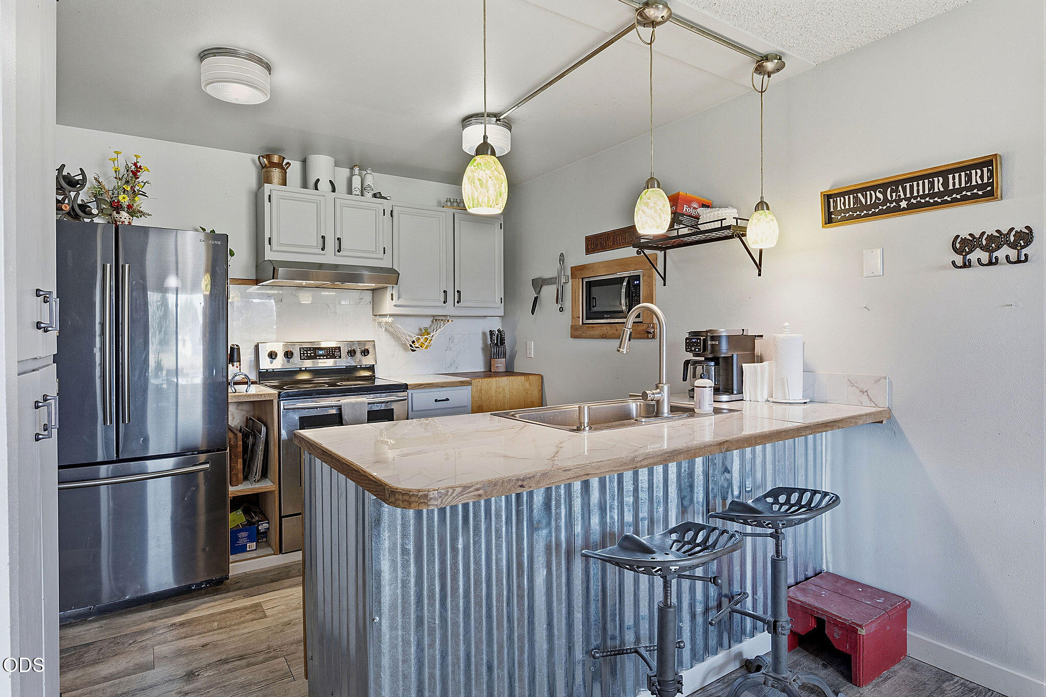 Kitchen with stainless steel appliances and a large corrugated-metal island with two bar stools.