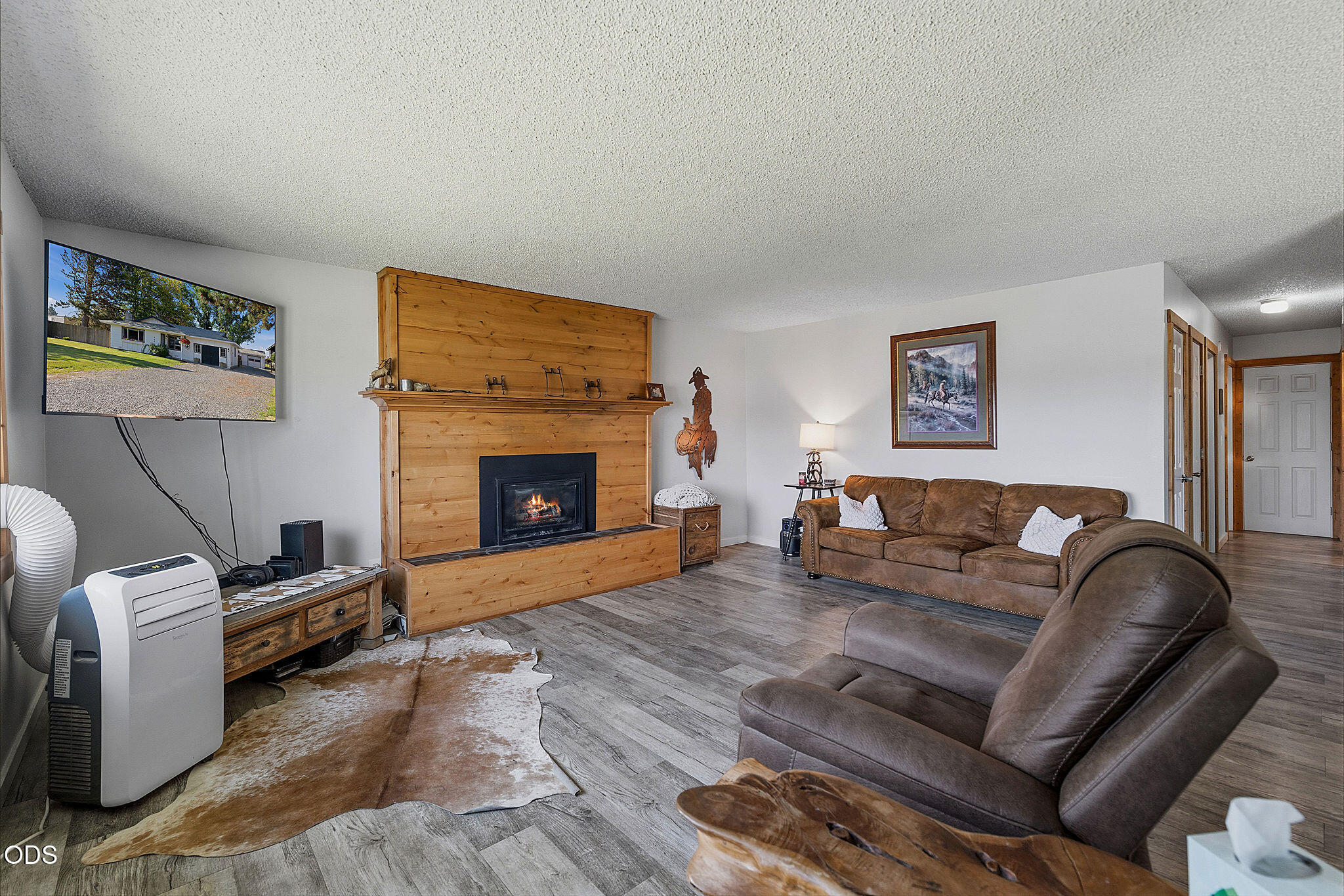 Living room with a large wood-surround fireplace, brown leather seating, and a cowhide rug.