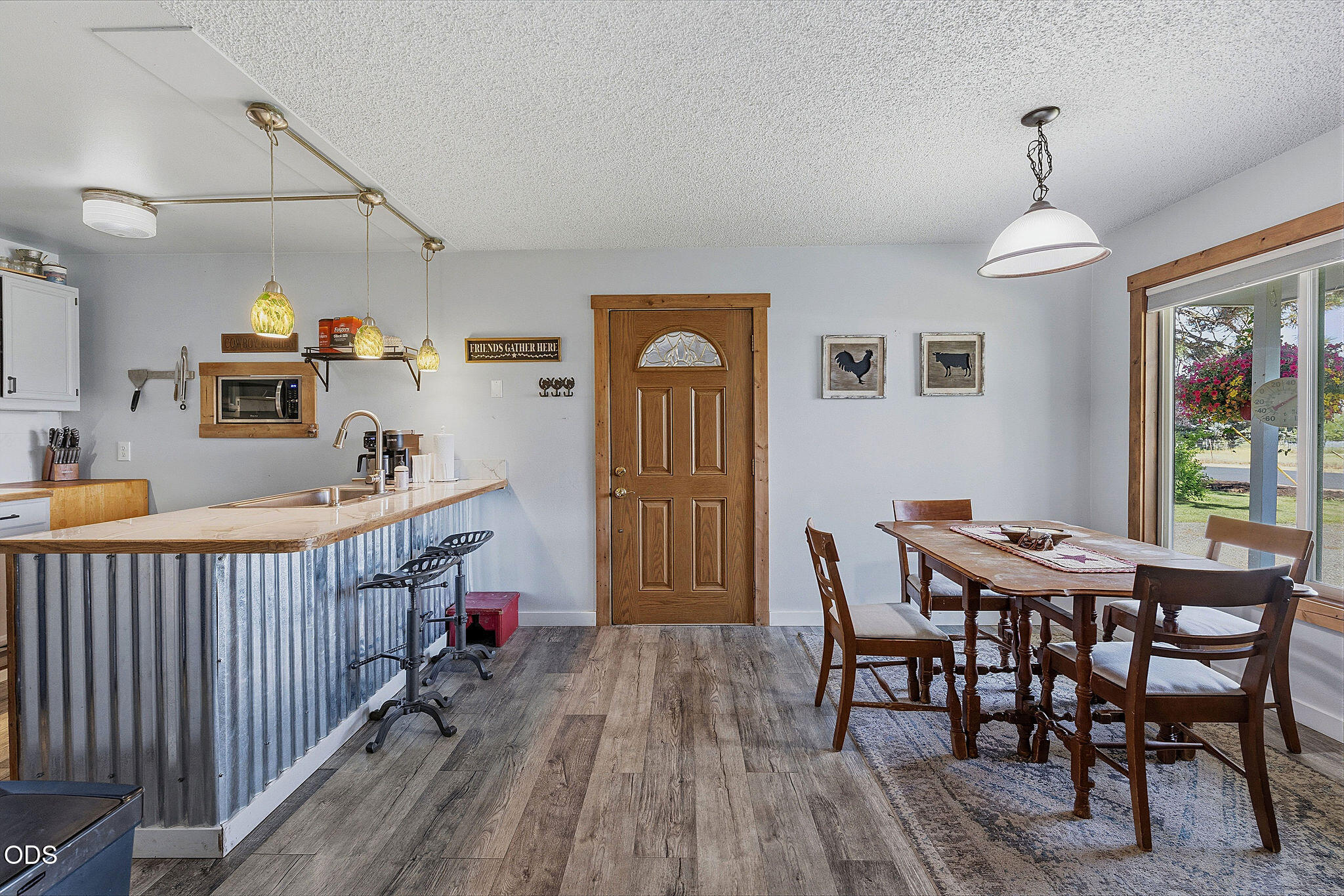 Kitchen and dining area with a corrugated metal breakfast bar and wood-trimmed door.