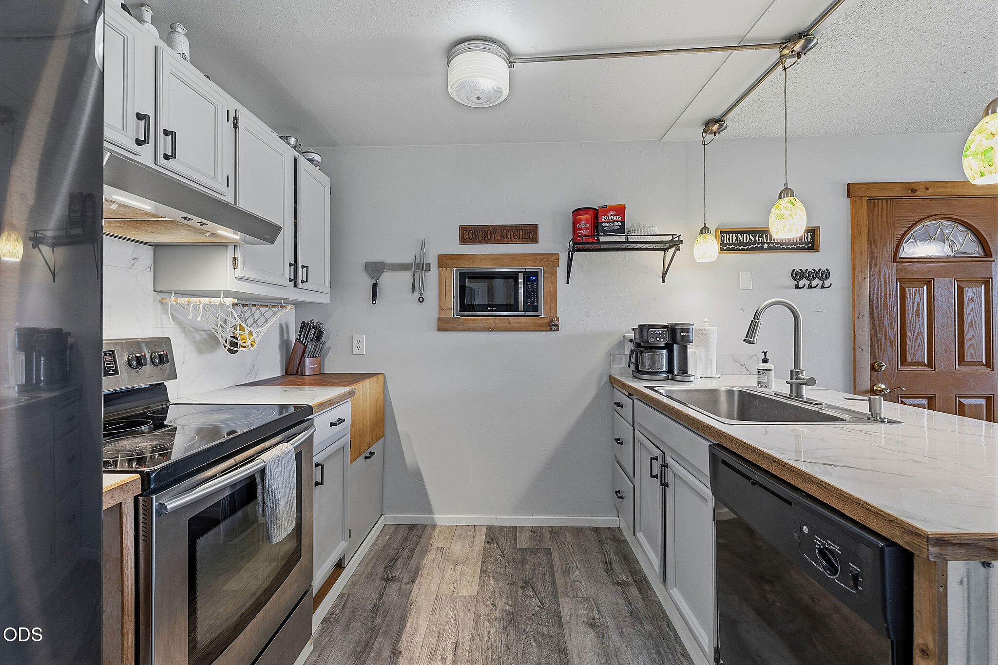 Kitchen with white cabinets, marble-look counters, stainless appliances, and a microwave set into the back wall.