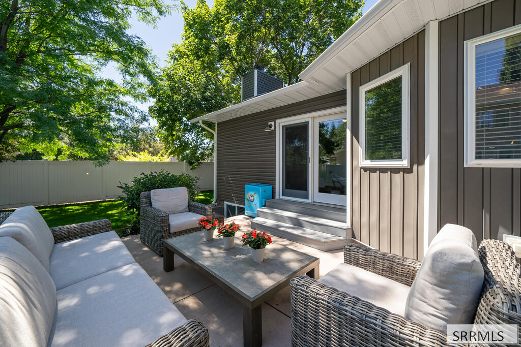 Backyard patio with wicker seating, a coffee table, sliding glass doors, and a fenced lawn.