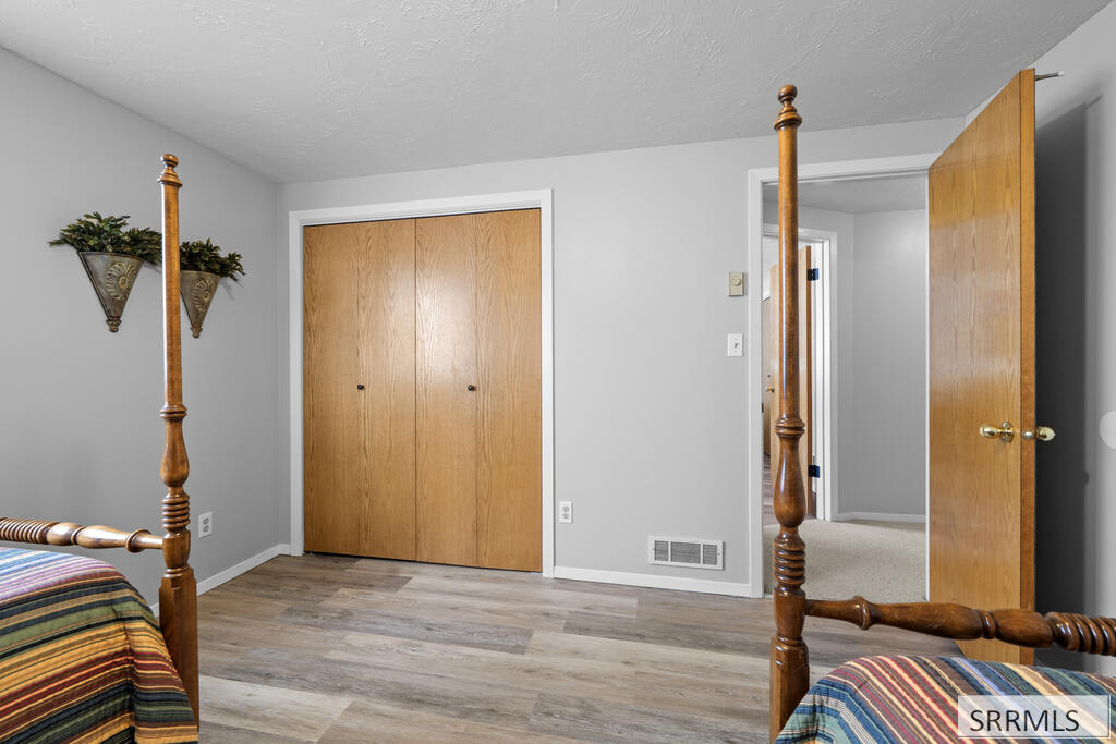 Bedroom with wooden closet doors, gray flooring, and carved bedposts.