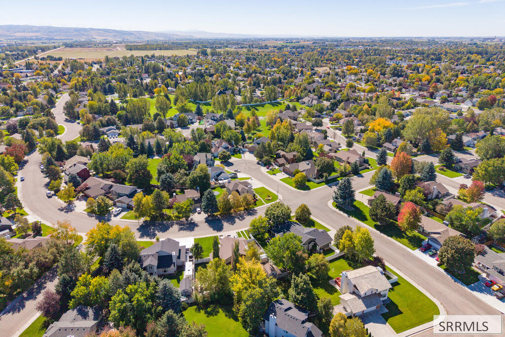 Aerial view of a leafy residential neighborhood with curved streets and autumn-colored trees.