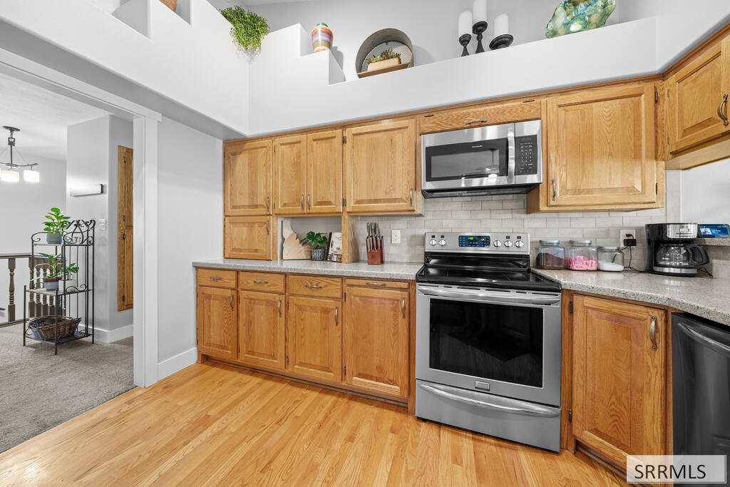 Kitchen with honey-toned wood cabinets, stainless steel appliances, and hardwood flooring.