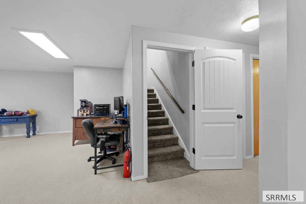 Basement office beside a carpeted staircase visible through an open white door.