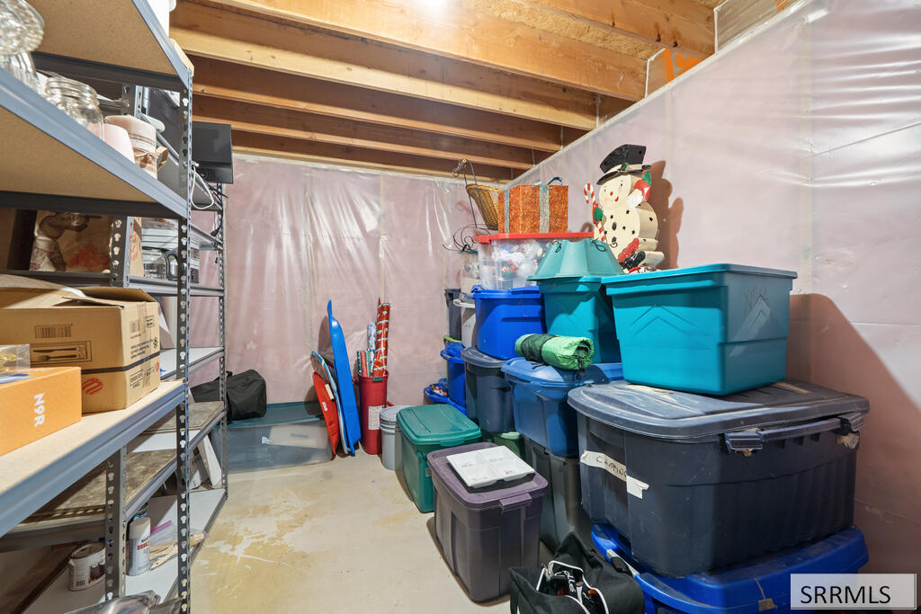 Basement storage area with stacked plastic bins, metal shelving, and exposed ceiling joists.