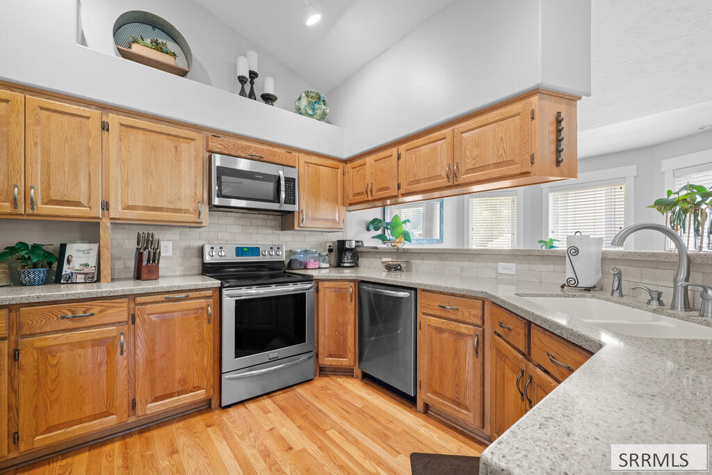 Kitchen with warm wood cabinetry, stainless appliances, granite counters, and a double-basin sink.