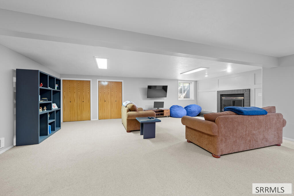 Furnished basement family room with brown sofas, blue beanbag chairs, and a fireplace.