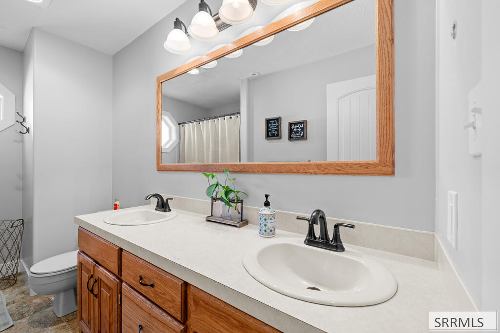 Bathroom with a double-sink vanity, warm wood cabinets, and a large wood-framed mirror.