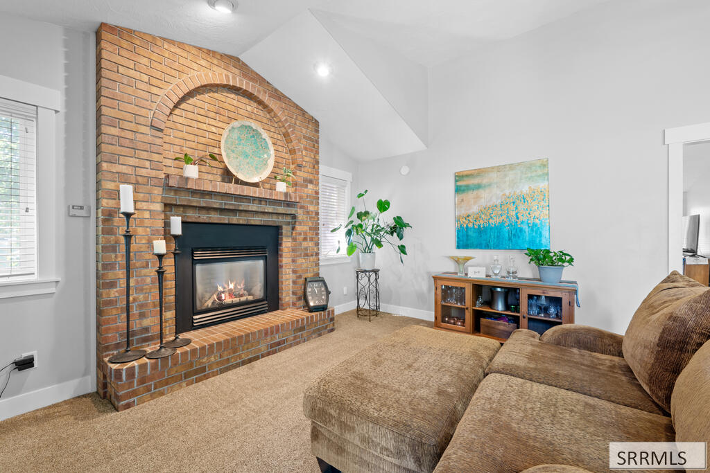 Living room with an arched brick fireplace, lit gas insert, and brown sectional sofa.