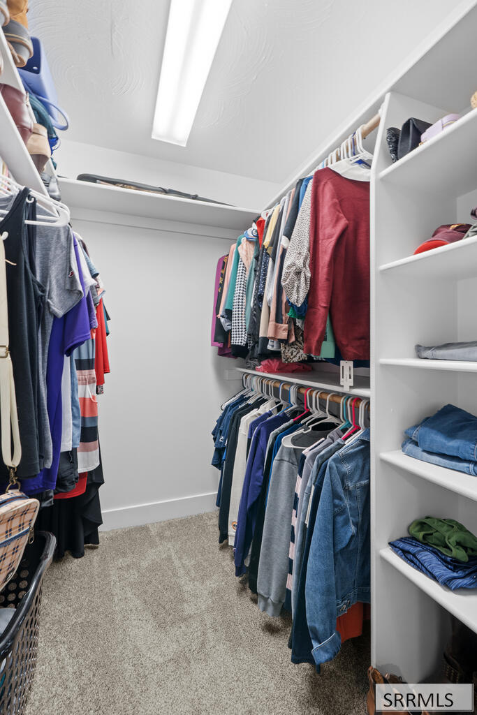 Walk-in closet with built-in shelves and double hanging rails filled with clothing.