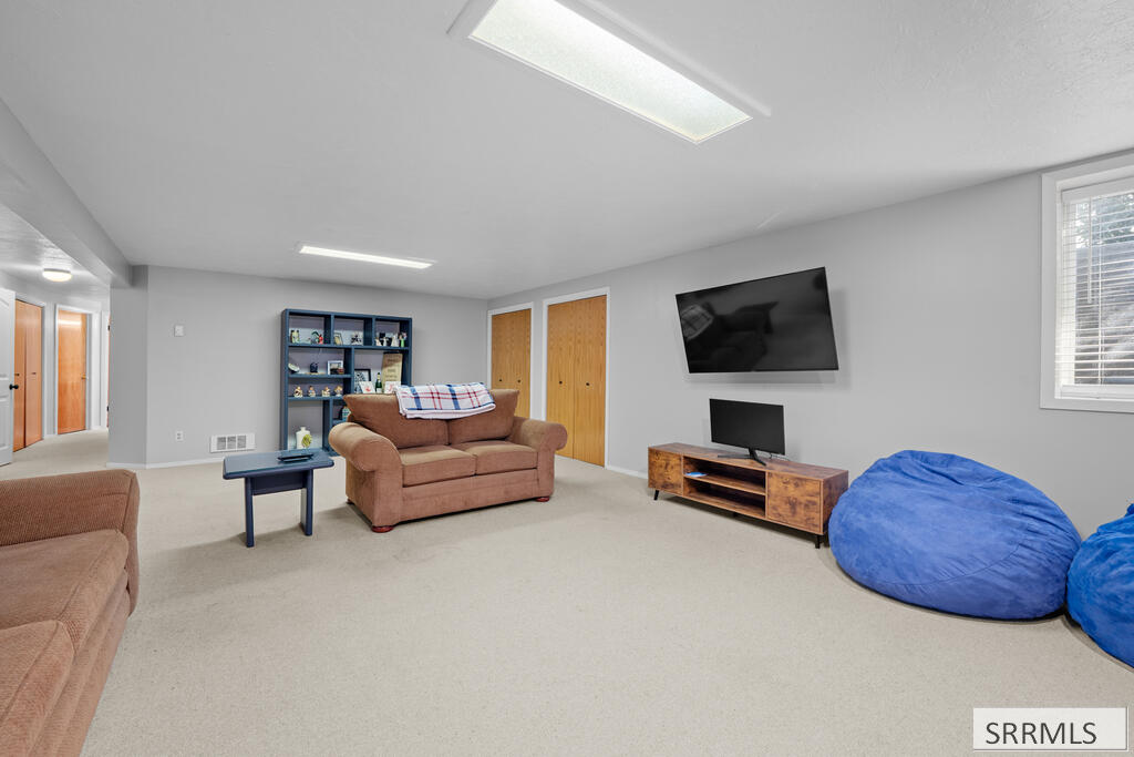 Furnished family room with a brown loveseat, wall-mounted television, and large blue beanbag chairs.