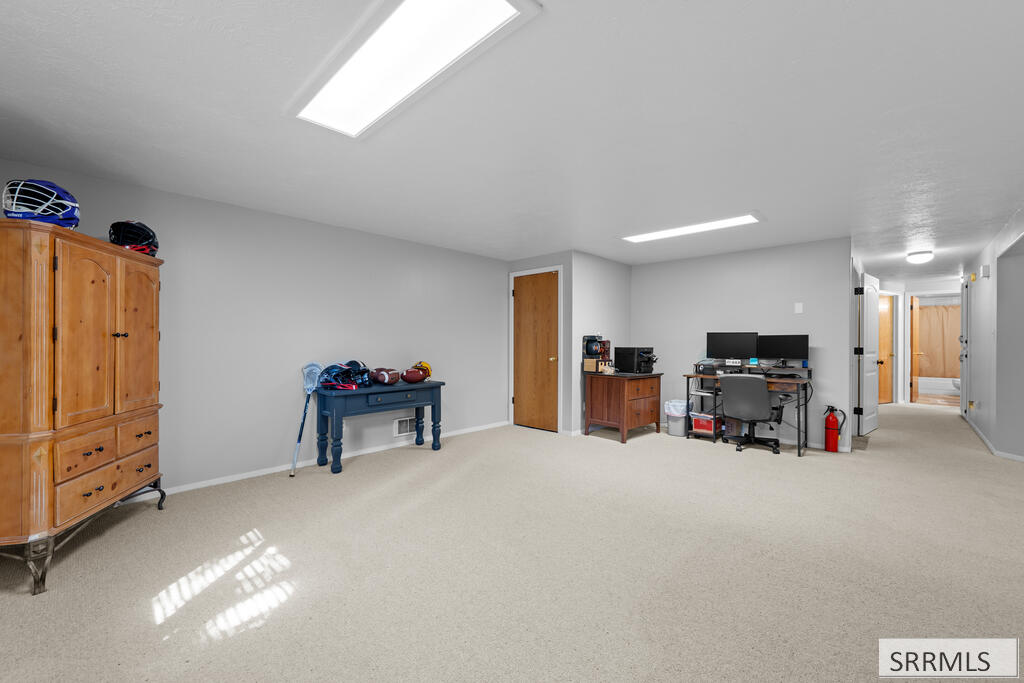 Carpeted room with a wooden armoire, sports equipment, and a computer desk.