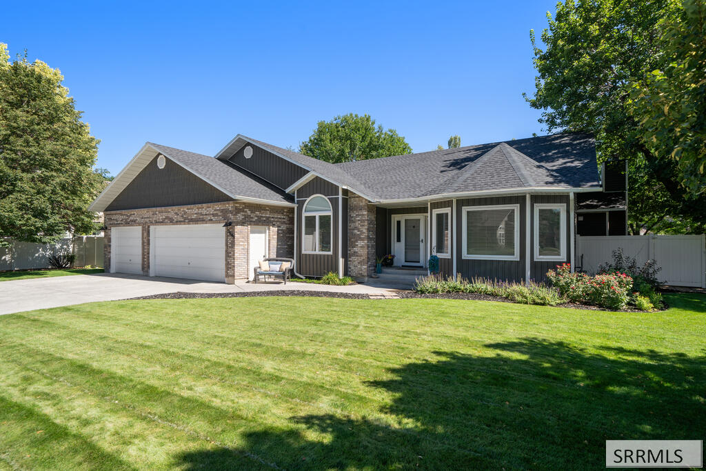 Single-story brick-and-siding home with a two-car garage, broad lawn, and landscaped entry.