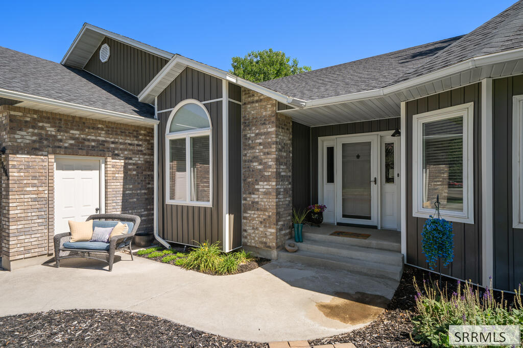 Home exterior with a covered entry, brick and dark siding, and an arched window.