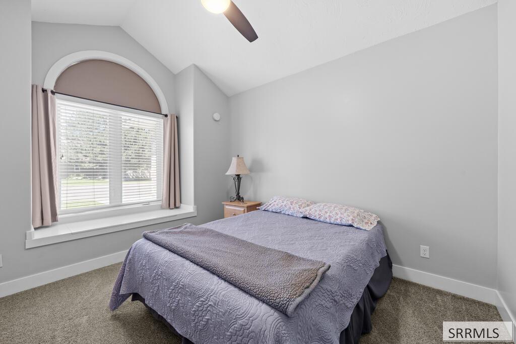 Bedroom with a lavender-quilted bed beneath a large arched window.