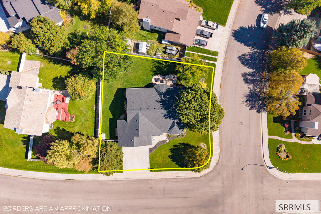 Aerial view of a house and landscaped lot, outlined in yellow beside a residential street.