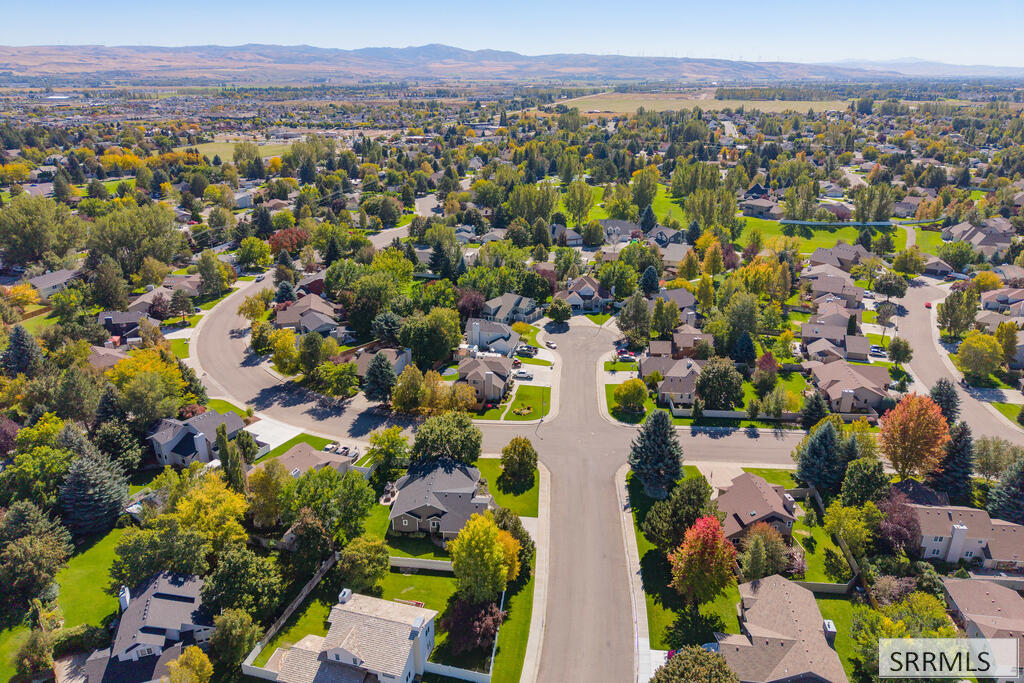 Aerial view of a residential neighborhood with tree-lined streets and distant mountain ridges.