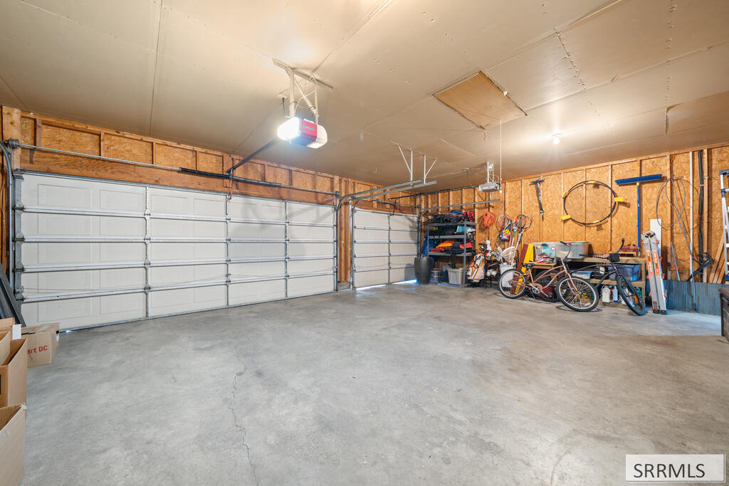 Spacious garage with two white doors, a concrete floor, and bicycles and sports gear along one wall.