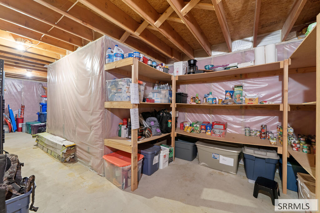 Unfinished basement storage area with stocked wooden shelves and plastic storage bins.