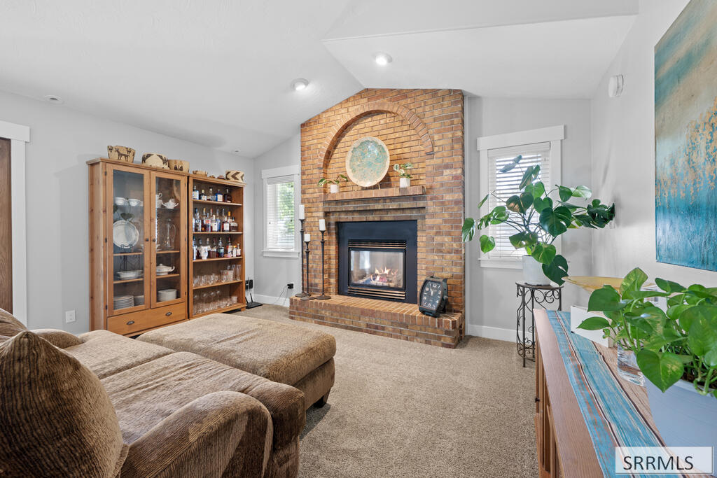 Furnished living room with a brick fireplace and beige sectional sofa.