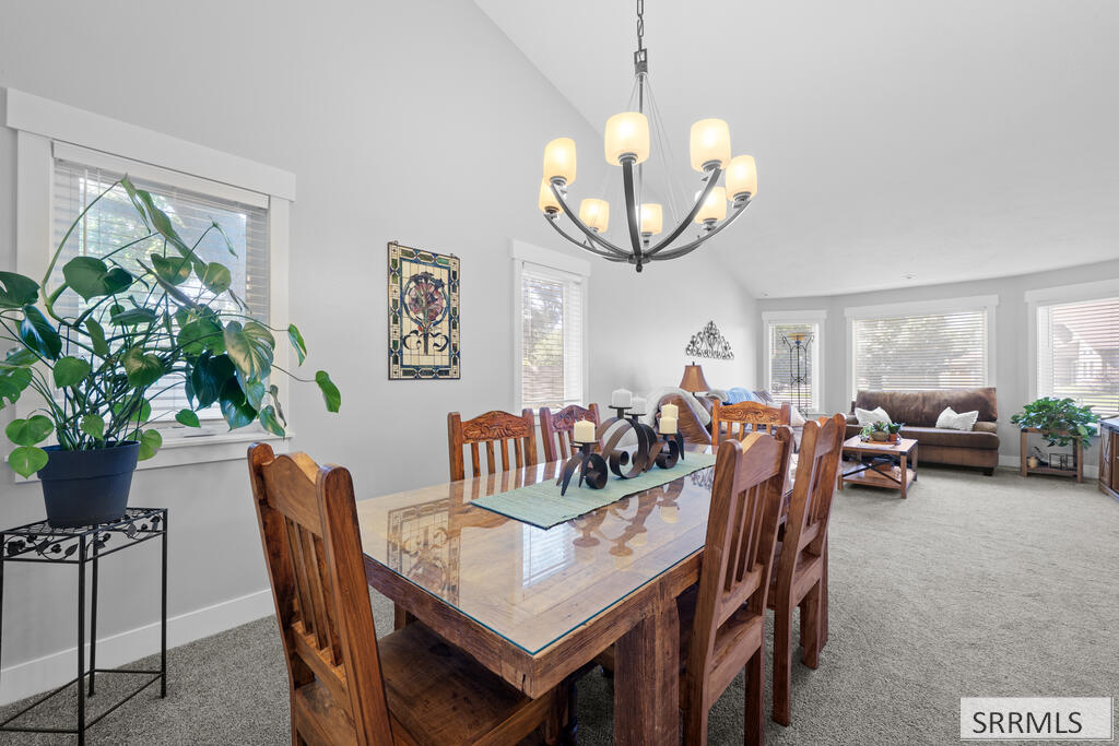 Dining room with a glass-top wooden table and chandelier, opening into a bright living area.