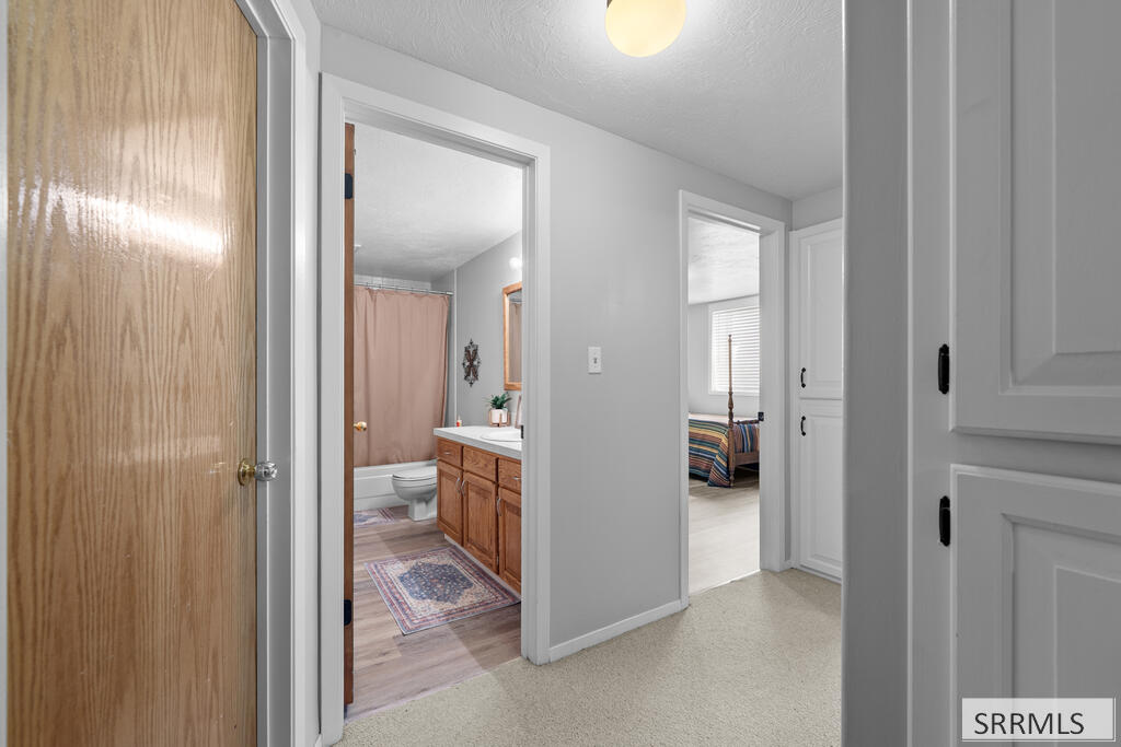 Hallway opening onto a bathroom with a wood vanity and a bedroom beyond.
