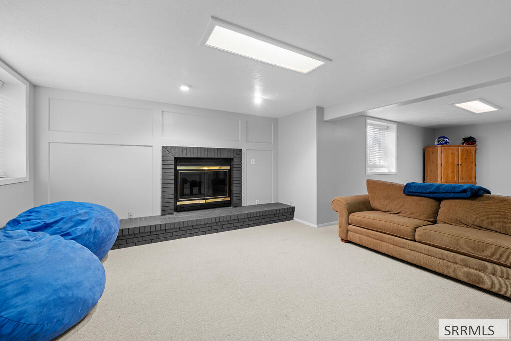 Basement living room with a brick fireplace, tan sofa, and blue beanbag chairs.